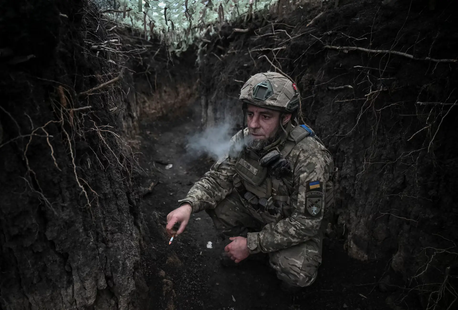 Ukrainian soldier in trench, breath visible in freezing cold